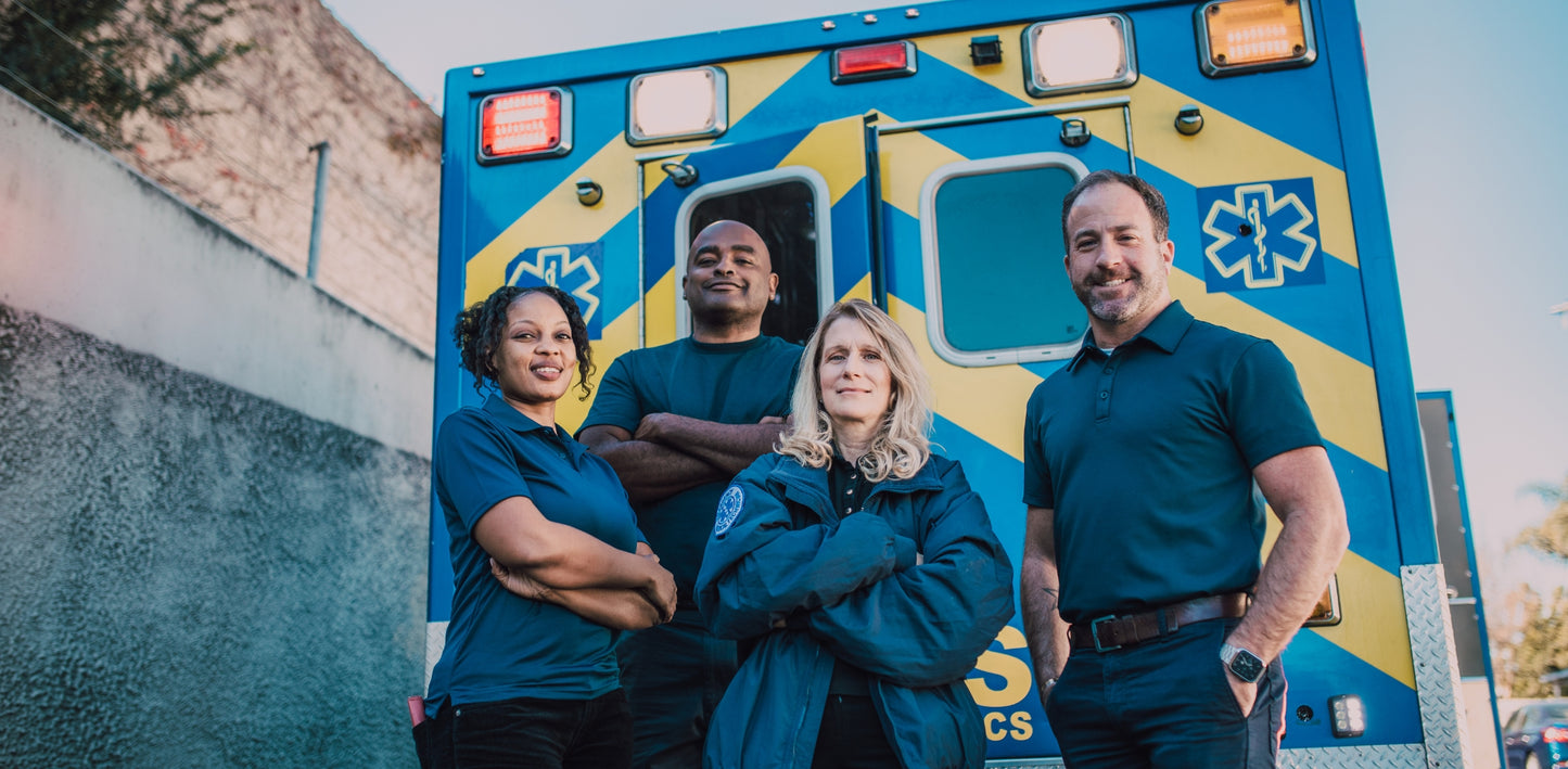Four paramedics standing in front of an ambulance with a blue and yellow design.