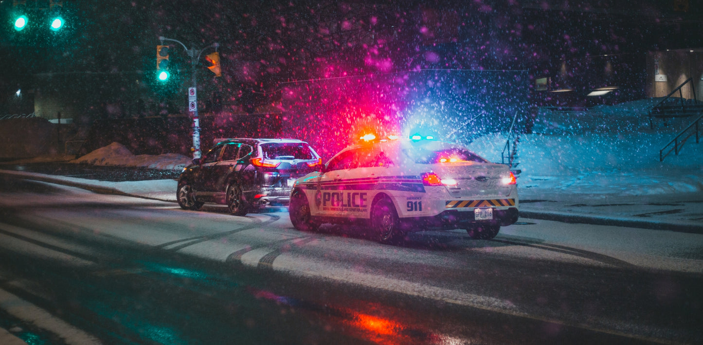 Police car with flashing lights on a snowy street at night